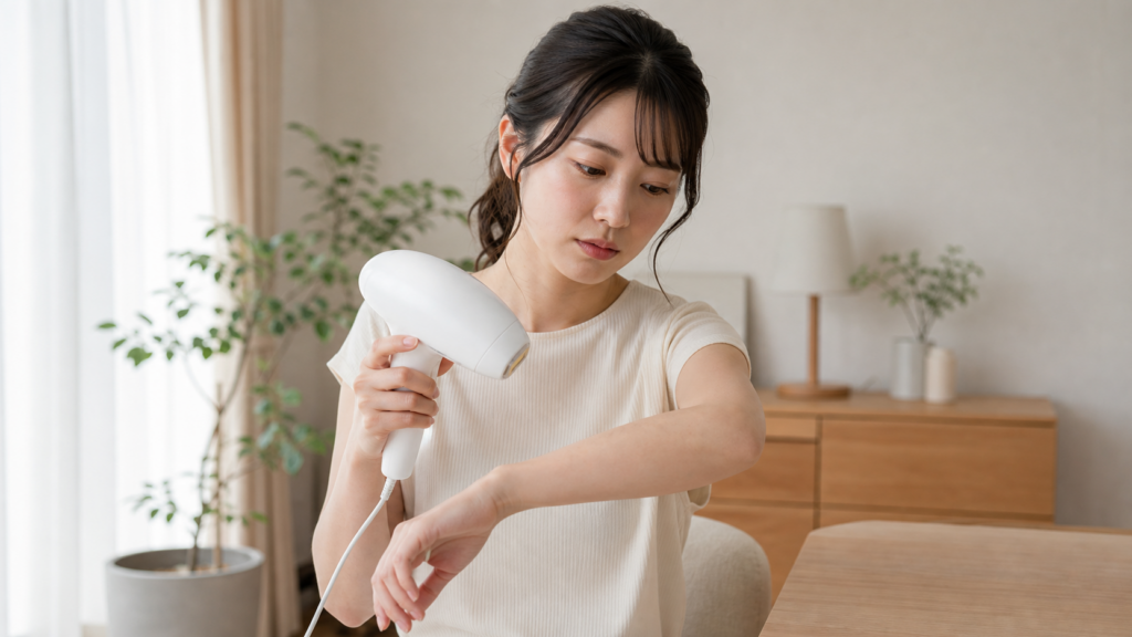 家庭用脱毛器を腕に近づけ、照射後の毛や肌の変化を確認する日本人女性